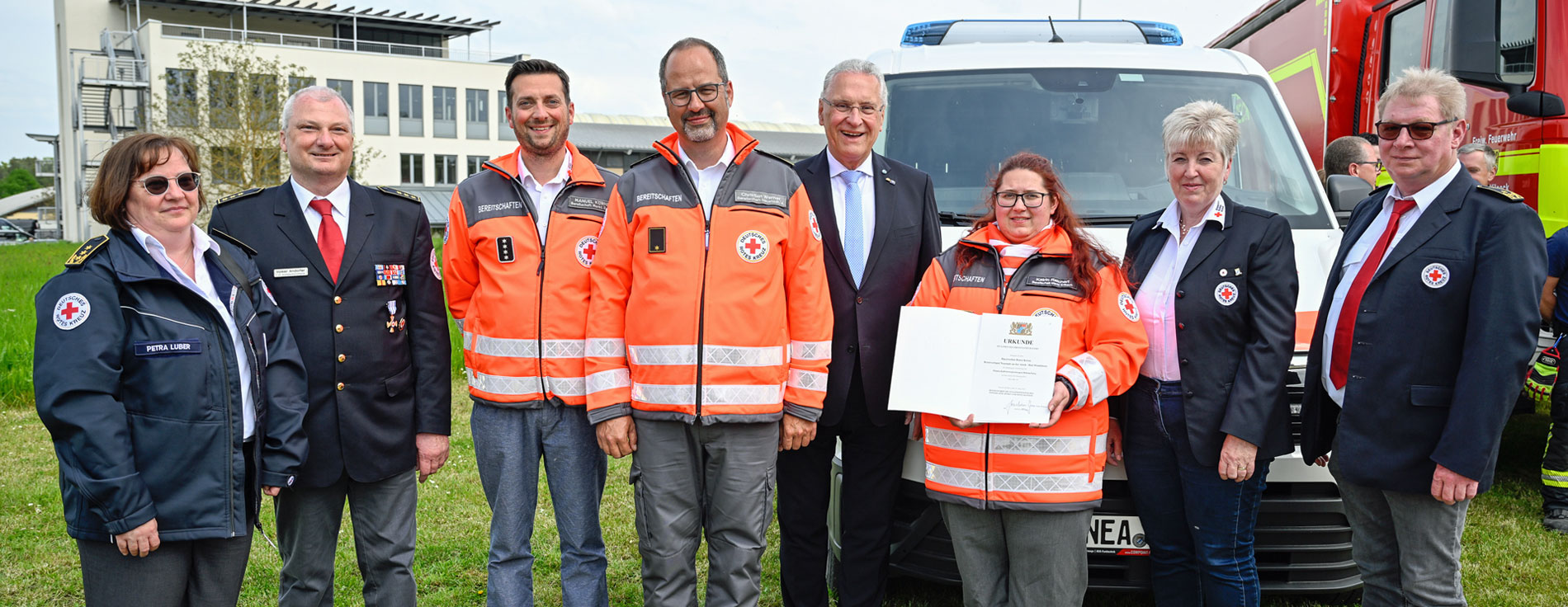 Gruppenfoto vor neuem Fahrzeug: Einsatzkräfte des BRK, Innenminister Herrmann und BRK-Präsidentin Angelika Schorer