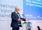 Herrmann auf Bühne mit Präsentation hinter Rednerpult