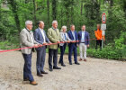 Innenminister Joachim Herrmann und weitere Personen hinter symbolischem Absperrband vor der Eröffnung des Radwegs