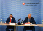 Innen- und Integrationsminister Joachim Herrmann und Geschäftsführer der Regionaldirektion von der Bundesagentur für Arbeit, Ralf Holtzwart, am Konferenztisch mit Mikrofon und Namensschild