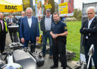 Innenminister Joachim Herrmann und weitere Personen mit Blick zu Motorrad neben ADAC-Stand
