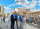 Gruppenfoto vor Neubaugerüst und festlichem Richtfestkranz in der Luft