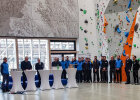 Herrmann und Weitere an Stehtischen, rechts Bergführer/innen vor Kletterwand