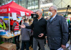 Herrmann und Reiter am Bahnhof neben Caritas-Stand