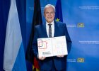 Sportminister Joachim Herrmann hält ein aufgeklapptes Dokument mit Unterschriften