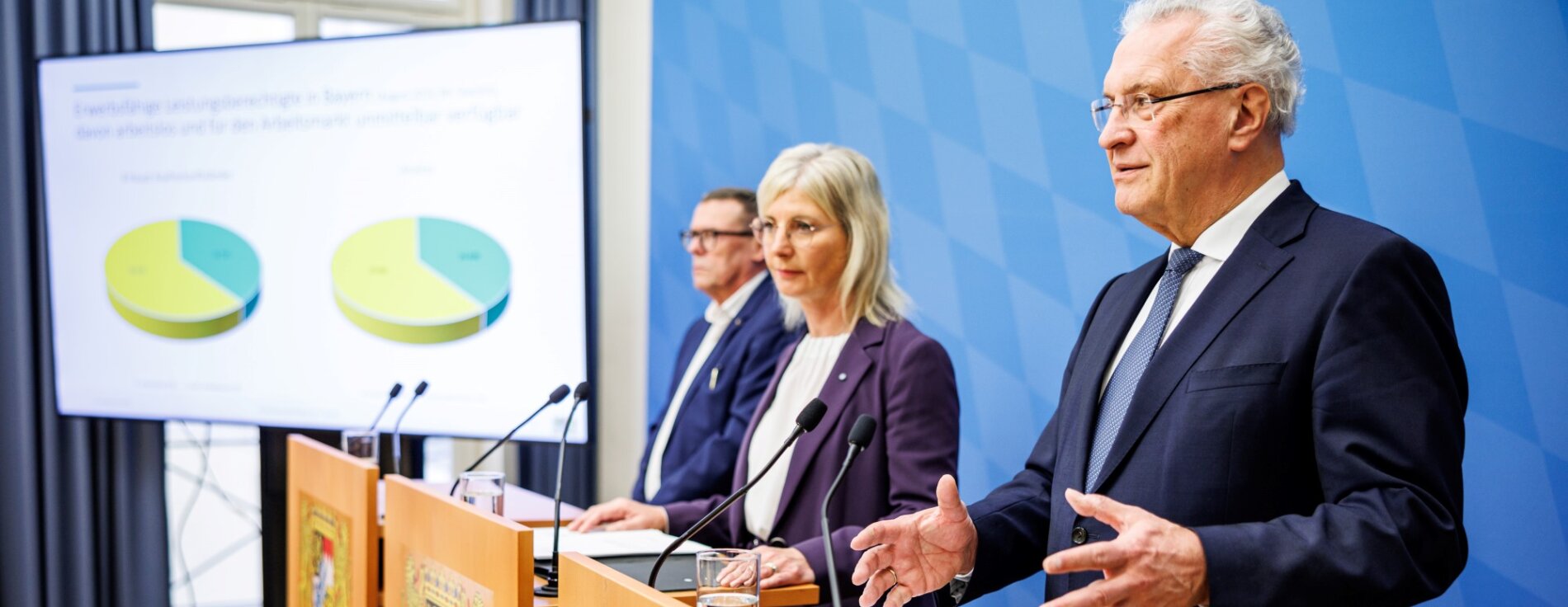 13. Dezember 2023: Bayern sichert Spitzenstellung bei der Integration in Arbeit: Arbeitsministerin Ulrike Scharf und Integrationsminister Joachim Herrmann haben heute in München gemeinsam mit dem Vorsitzenden der Geschäftsführung der Regionaldirektion Bayern der Bundesagentur für Arbeit, Ralf Holtzwart, die aktuellen Herausforderungen und Erfolge bei der Integration von Flüchtlingen in den bayerischen Arbeitsmarkt vorgestellt. Herrmann: „Die Integration in Arbeit gelingt nirgendwo so gut wie in Bayern! Viele Geflüchtete sind im Arbeitsmarkt angekommen, auch die ukrainischen Kriegsflüchtlinge fassen dort immer mehr Fuß.“ Herrmann, Scharf und Holtzwart an Rednerpulten, im Hintergrund Präsentation