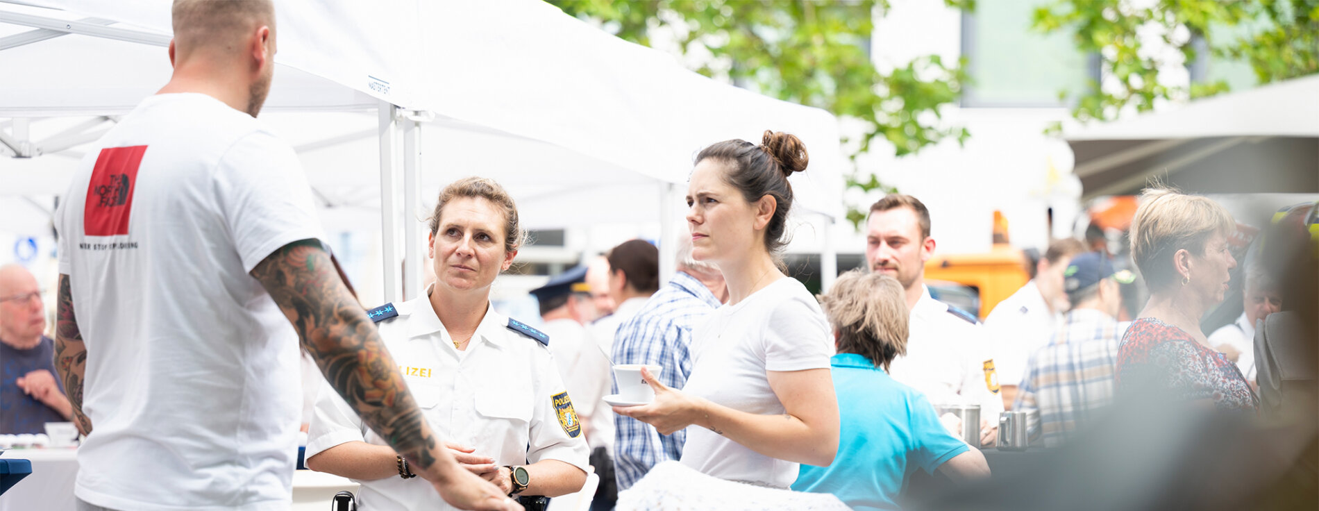 Joachim Herrmann hat in Erlangen das neue Format der Bayerischen Polizei ‚Coffee with a Cop’ vorgestellt: „Bei regionalen Veranstaltungen lädt die örtliche Polizei Bürgerinnen und Bürger auf ein Getränk ein, um ins Gespräch zu kommen.“ Polizistin im Bürgergespräch am Polizeistand