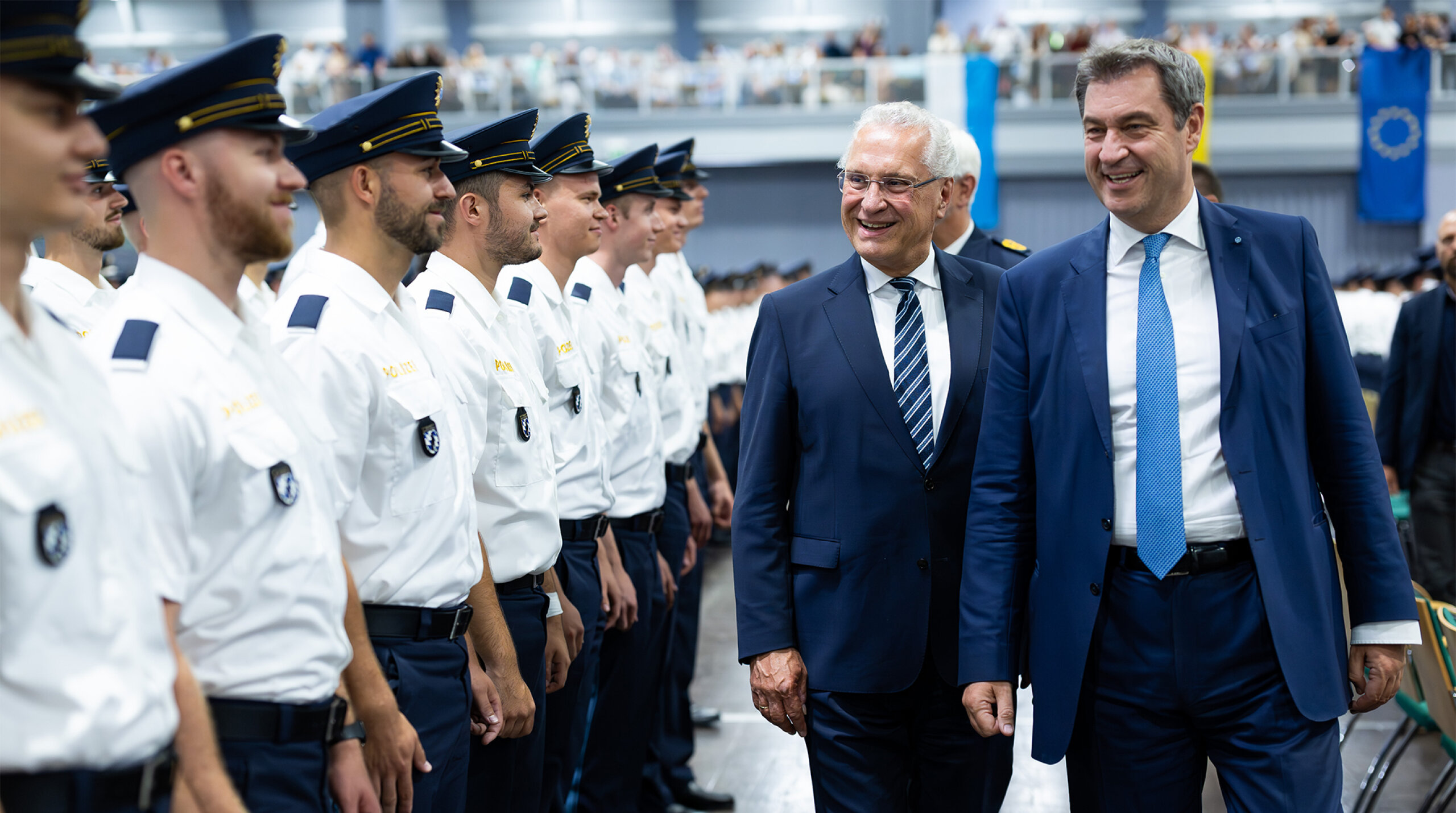 Ministerpräsident Dr. Markus Söder und Innenminister Joachim Herrmann gehen an neuen Polizistinnen und Polizisten lächelnd vorbei