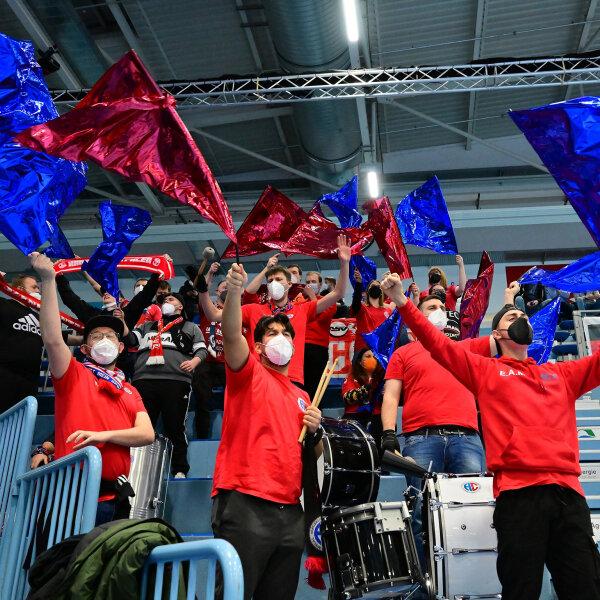 Fans im Stadion mit schwenkenden Fahnen bei Handball-Pokal-Spiel