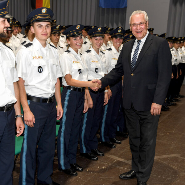 Innenminister Joachim Herrmann schüttelt einer der vereidigten Polizistinnen und Polizisten die Hand