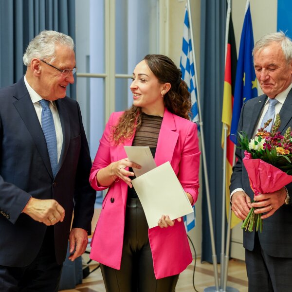 Herrmann überreicht freudig Nathalie Gellner eine Urkunde, Joseph Ströbl überreicht einen Blumenstrauß