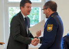 Staatssekretär Sandro Kirchner gratuliert mit Handschlag Polizeioberrat Marco Di Blasio