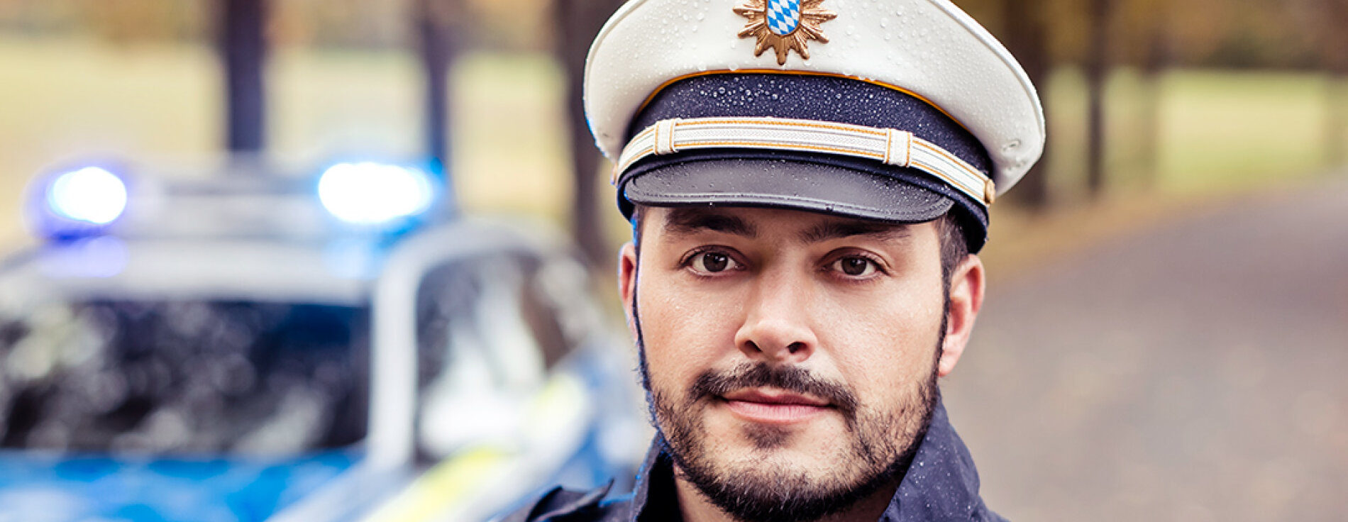 Polizist in Uniform vor Streifenwagen