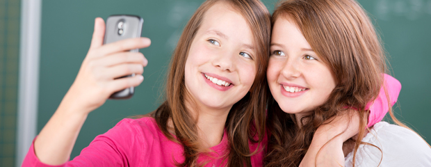 Wir wollen für das Thema Medienkompetenz sensibilisieren Zwei Mädchen fotografieren sich mit dem Handy