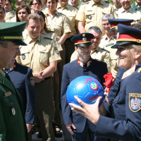 Eine leitende österreichische Polizeibeamtin überreicht einem bayerischen Einheitsführer als Dank einen Fußball.