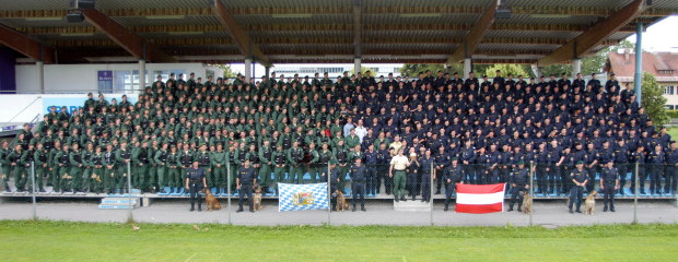 Bayerische und österreichische Polizeibeamte stellen sich in einer Stadiontribüne zu einem Gruppenfoto auf.